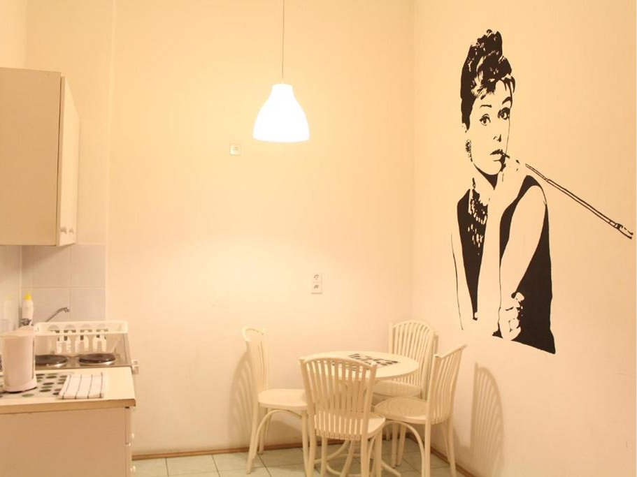 Mała kuchnia z metalowym zlewem, suszarką na naczynia, czajnikiem elektrycznym i dwupalnikową kuchenką elektryczną.